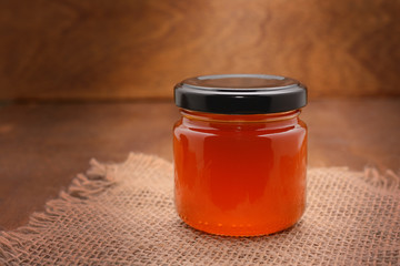 jar with honey on rough fabric with a wooden background