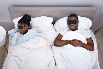 Couple Sleeping On Bed Using Eye Mask