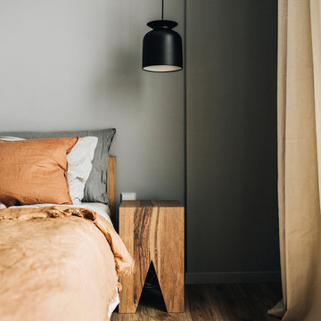 Modern Nordic Scandinavian interior design concept. Bedroom with bed, ginger bedcover, pillows, oak nightstand, designer pendant light, wooden floor. Elegant apartment for rent.