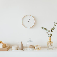 Modern interior design concept. Bright beige and golden apartment with clock, eucalyptus branch, vase, candle. © Floral Deco