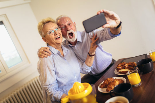 Smiling senior couple taking selfie at home