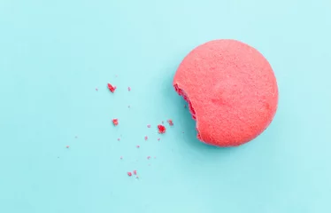 Fototapeten French macaron with missing bite isolated on cyan background © joey333