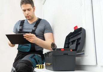 Professional contractor sitting at window with tablet pc.
