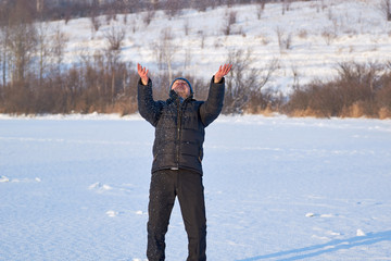 Fototapeta na wymiar young handsome guy in winter clothes fooling around throwing snow in nature in winter