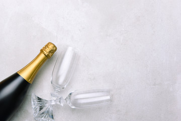 Champagne bottle and glasses on light gray surface.