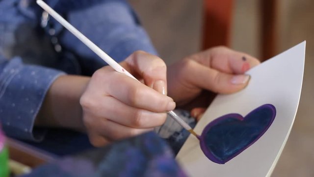 closeup of women artist hands painting on paper