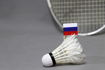 Mini Russia flag stick on the white shuttlecock on the grey background and out focus badminton racket.