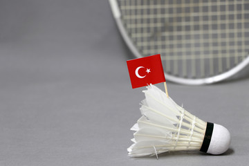 Mini Turkey flag stick on the white shuttlecock on the grey background and out focus badminton racket.