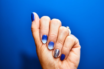 a feminine hand with painted nails in a colorful, hybrid varnish. - obrazy, fototapety, plakaty