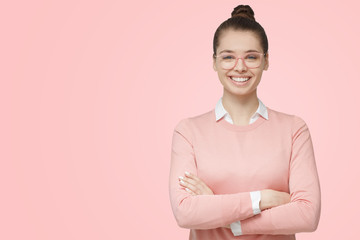 Portrait of young good-looking european woman standing with crossed arms, wearing eyeglasses and...