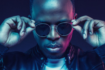 Close-up studio shot of african american male model wearing trendy sunglasses and leather jacket
