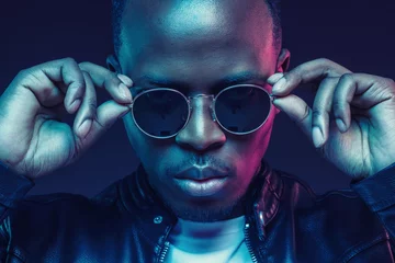 Nahaufnahme Studioaufnahme eines afroamerikanischen männlichen Models mit trendiger Sonnenbrille und Lederjacke © Damir Khabirov