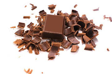Delicious black chocolate shavings and pieces on white background, top view