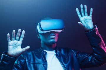 African american man in vr glasses, playing video games with virtual reality headset, trying to touch something with hands