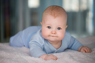 Portrait of a baby boy who lies on his stomach in a blue suit