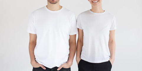 Young smiling couple in blank white t-shirts isolated on gray background