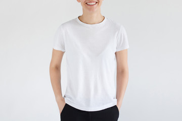 Young woman standing with hands in pockets, wearing blank white t-shirt with copy space for your...