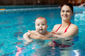 Fototapeta na wymiar baby with mom learns to swim in the pool