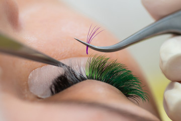 The master builds up large colored eyelashes to the client. Preparation for beauty photography....