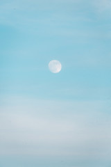 The moon in a blue daytime sky