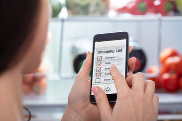 Woman Marking Shopping List On Mobile Phone
