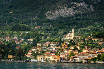 Fototapeta premium Widok na wieś w lesie w jeziorze Como z promu o zachodzie słońca, Jezioro Como, Włochy