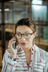 Appealing woman wearing blue earrings speaking on the phone