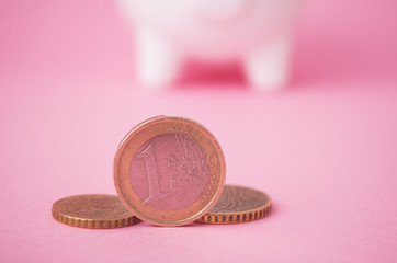 closeup of  euros coins in front of yellow piggy bank on green background