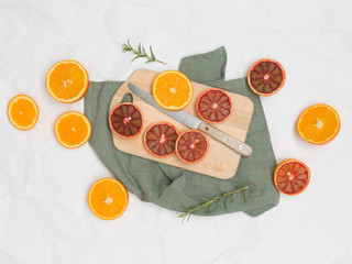 beautiful still life with blood oranges on white paper background and wooden board and knife