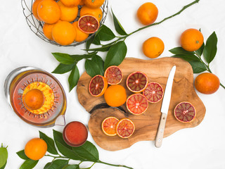 beautiful still life with blood oranges on white paper background and wooden board and knife