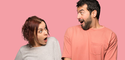 Couple in valentine day with surprise and shocked facial expression over isolated pink background