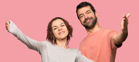Couple in valentine day presenting and inviting to come over isolated pink background