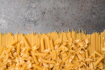 Different types of pasta that we use every day in the kitchen when cooking. View from above. Products flat-lying. Place for a description or text. A product made of flour and eggs. - obrazy, fototapety, plakaty