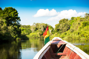 Bolivian flag on small boat cruising river through the pampas near Rurrenabaque