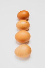 Different brown zwf on a white background lie in a row behind each other. Four chicken fresh delicious eggs in a row.
