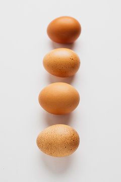 Different brown zwf on a white background lie in a row behind each other. Four chicken fresh delicious eggs in a row.