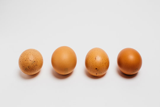 Different brown zwf on a white background lie in a row behind each other. Four chicken fresh delicious eggs in a row.
