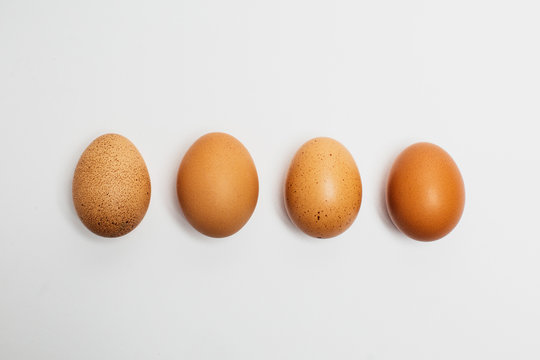 Different brown zwf on a white background lie in a row behind each other. Four chicken fresh delicious eggs in a row.