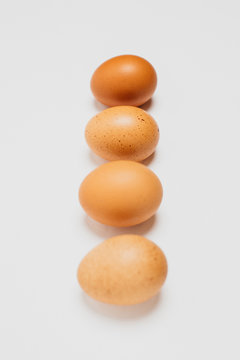 Different brown zwf on a white background lie in a row behind each other. Four chicken fresh delicious eggs in a row.