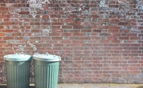 trash can rubbish bin dustbins garbage trashcan can outside against brick wall background with copy space - stock photo, stock footage
