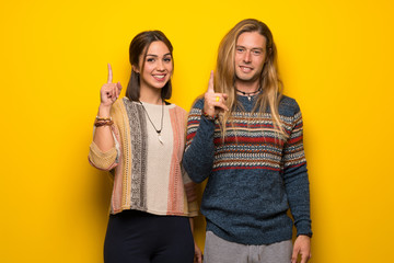 Hippie couple over yellow background showing and lifting a finger in sign of the best