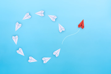 Group of white paper planes fly in a circle and one red paper plane pointing in different way on blue background. Business for new ideas creativity, innovative and solution concept. - obrazy, fototapety, plakaty