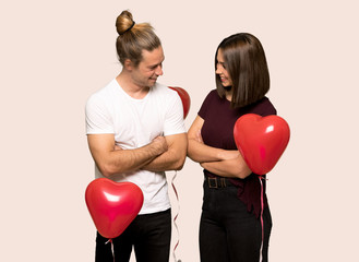 Couple in valentine day keeping the arms crossed while smiling over isolated background