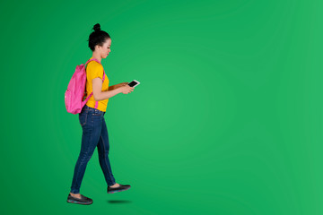 Asian female student walking with tablet on studio