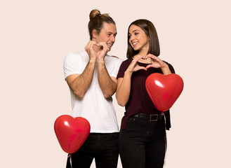 Fototapeta na wymiar Couple in valentine day making heart symbol by hands over isolated background