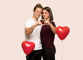 Fototapeta na wymiar Couple in valentine day making a heart with hands over isolated background