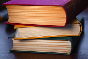 old large books with red, yellow and green covers are on a wooden table