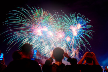 Crowd watching fireworks and celebrating city founded. Beautiful colorful fireworks display in the urban for celebration on dark night background.