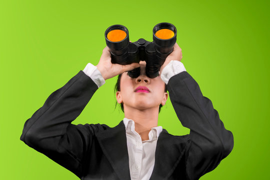 Young businesswoman using binoculars on studio