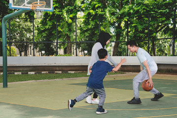 Young Muslim family playing basketball in the field